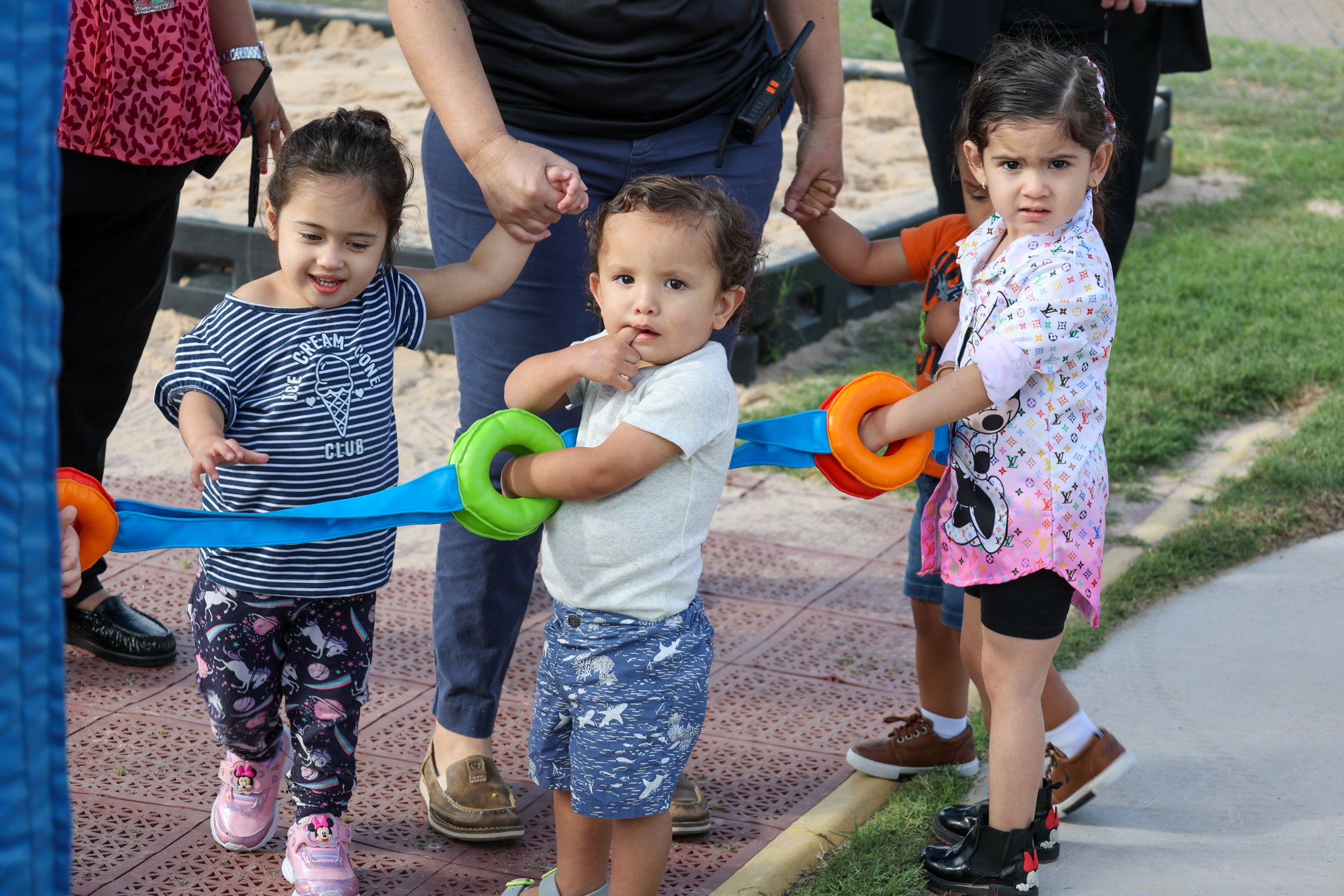 toddlers holding walking rope looking at camera